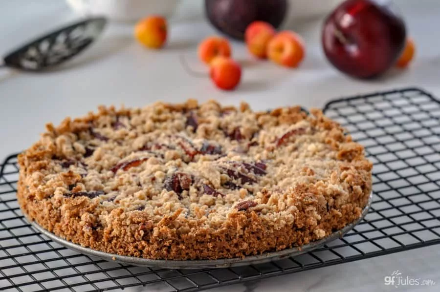 gluten free plum tart on rack with cherries