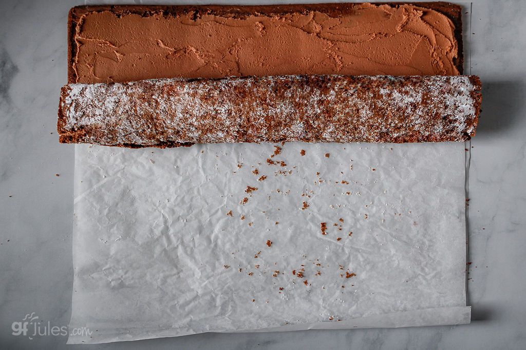 rolling up frosted gluten free chocolate sponge cake for yule log