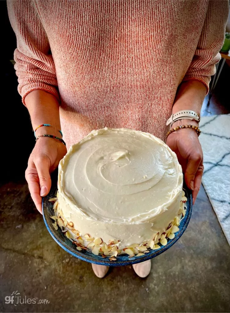 gluten free carrot cake with vegan frosting and almonds held by jules