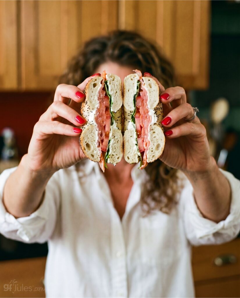 jules holding gluten free bagel sandwich cut in half