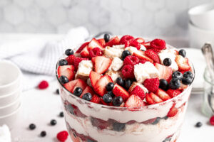 Gluten Free Berry Trifle layered in a glass trifle bowl with fluffy gfJules angel food cake, fresh strawberries, blueberries, and raspberries, perfect for summer gatherings.
