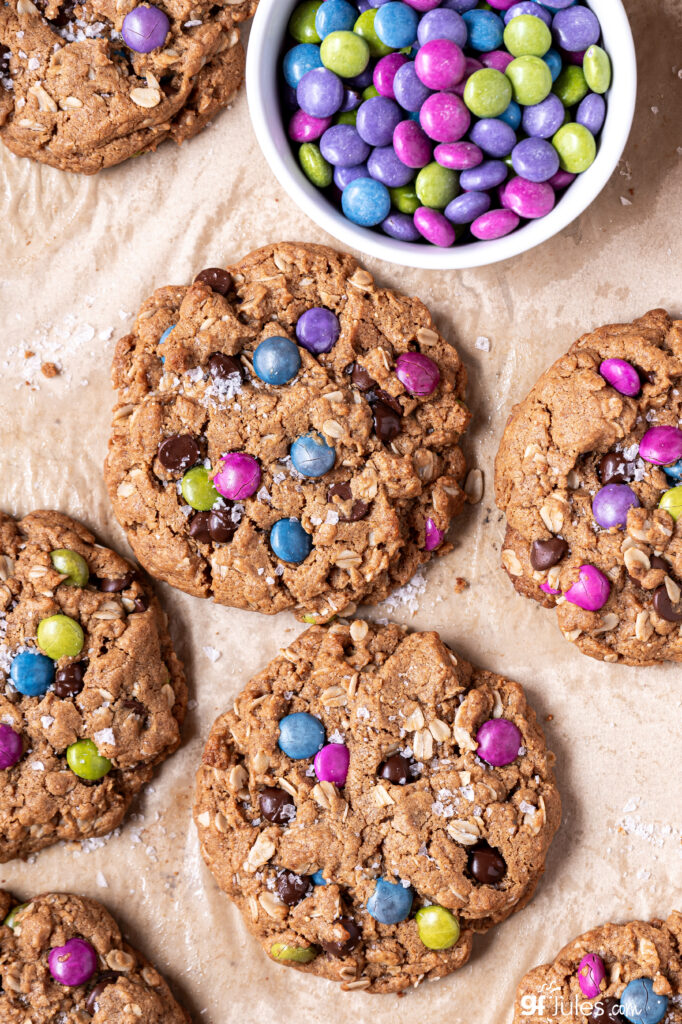 Soft and chewy gluten free monster cookies cooling on a baking sheet, full of peanut butter and oats.