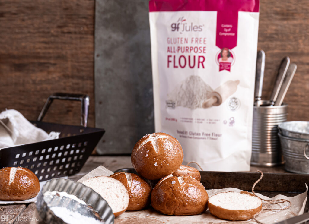 Golden-brown gluten free pretzel rolls cooling on a baking tray, sprinkled with coarse salt, made with gfJules Gluten Free All Purpose Flour.