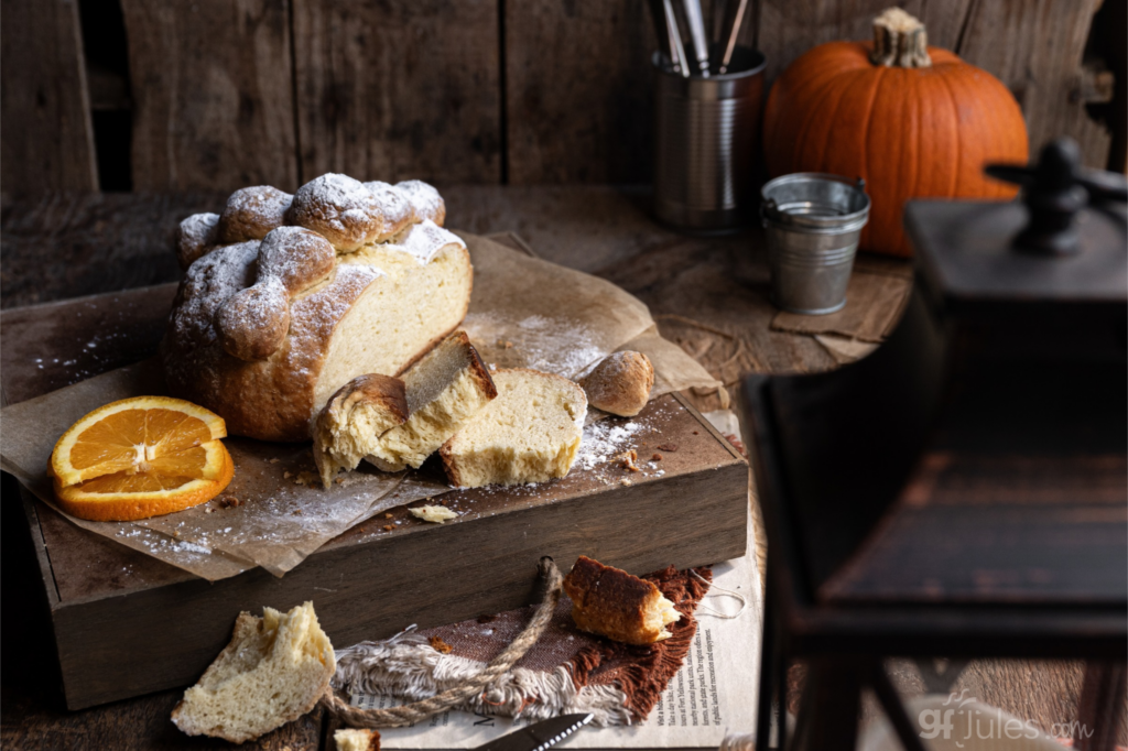 gluten free pan de muerto sliced on board with pumpkin